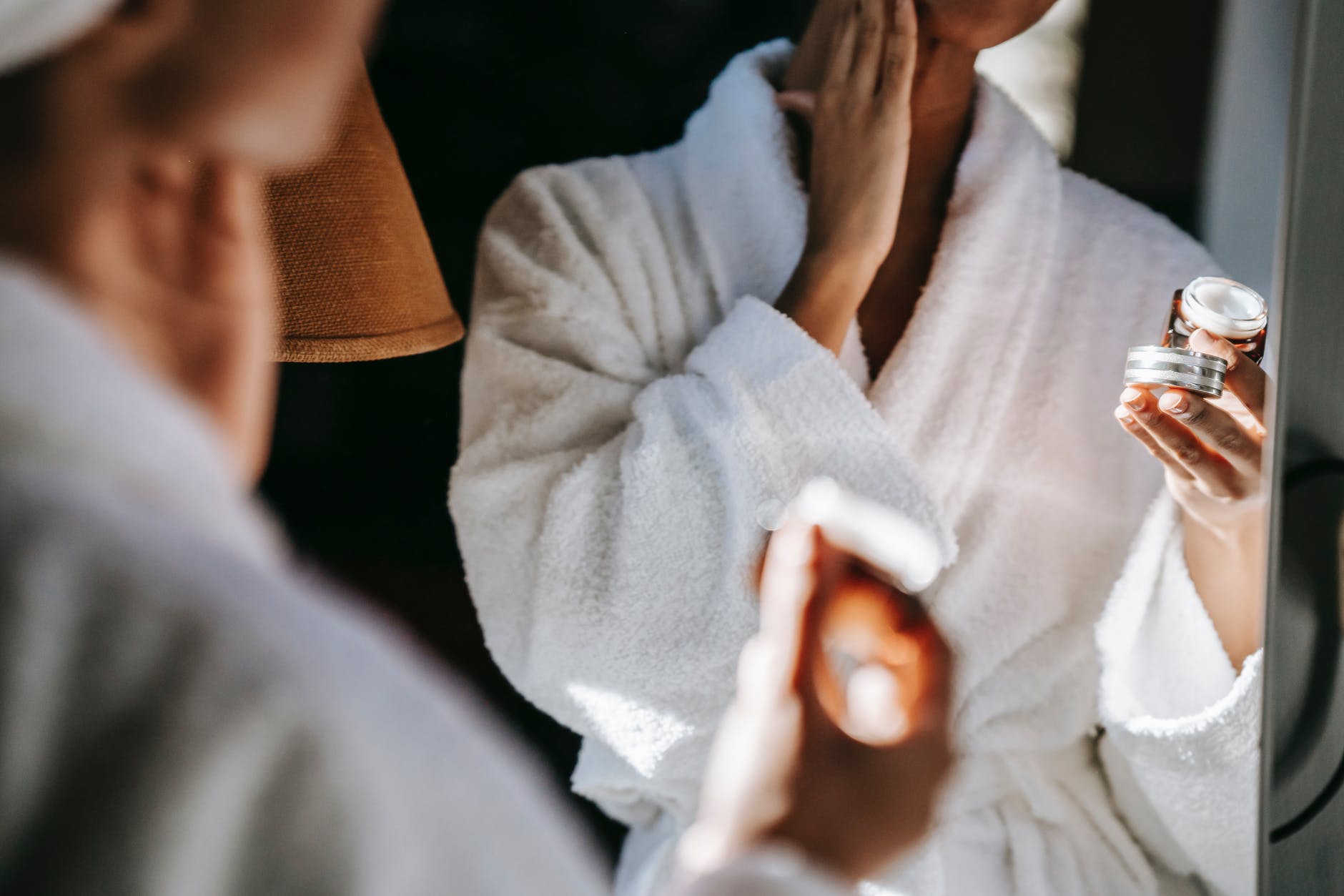 black woman applying cream in bathroom